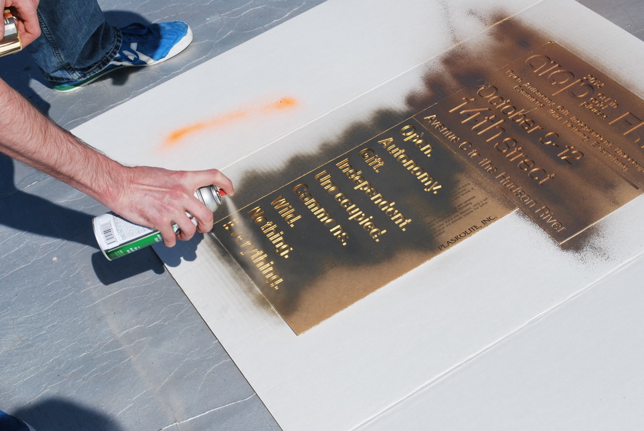 Spray painting a sign for AIOP:Free on a rooftop