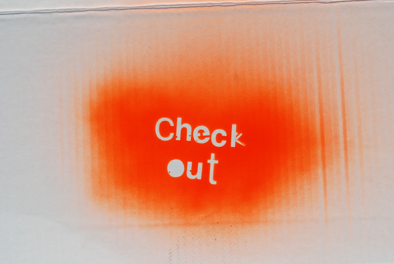 Bright orange spray painted stencil that says Check Out