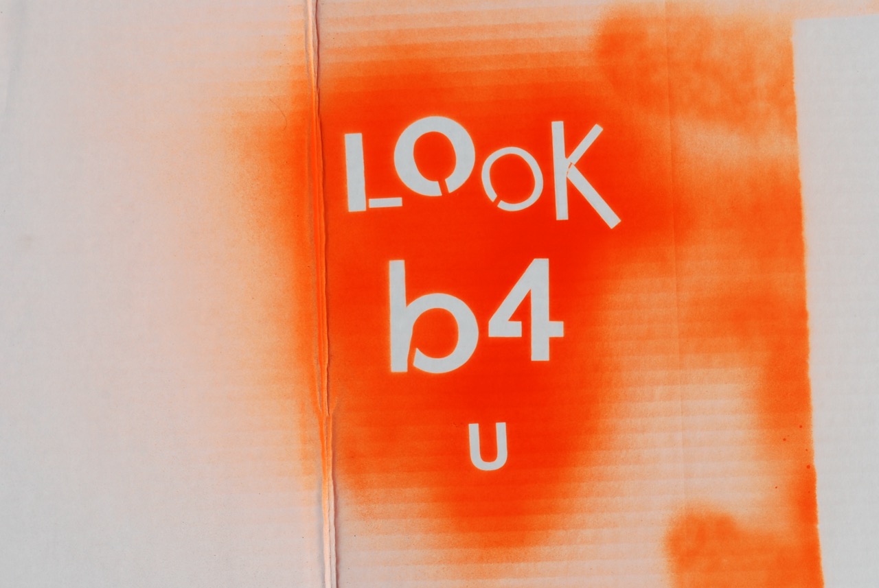 Bright orange spray painted stencil that says Look Before You